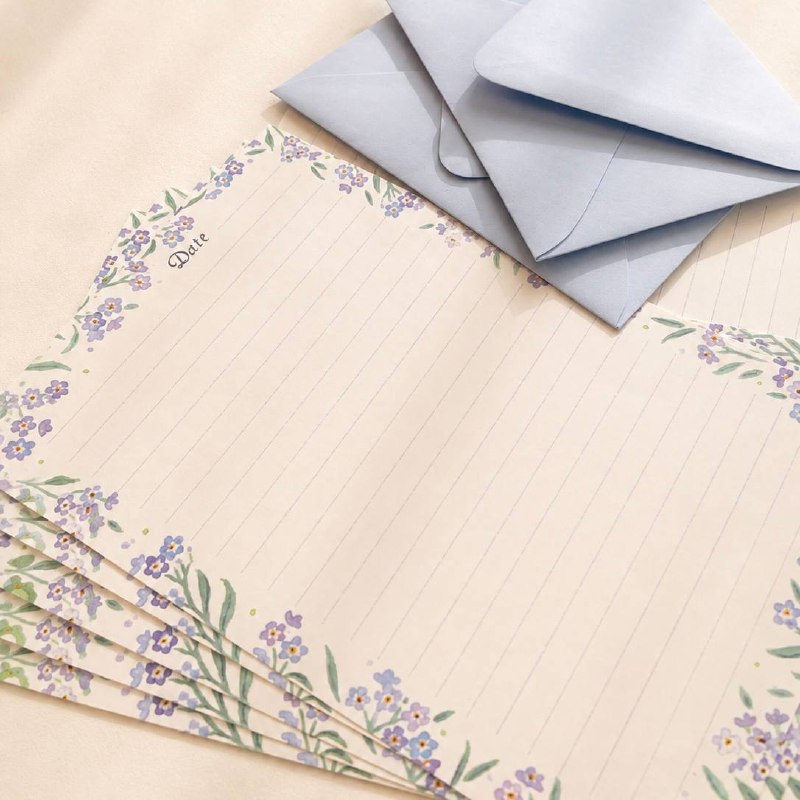 Forget-me-not writing sheets fanned beside powder-blue envelopes