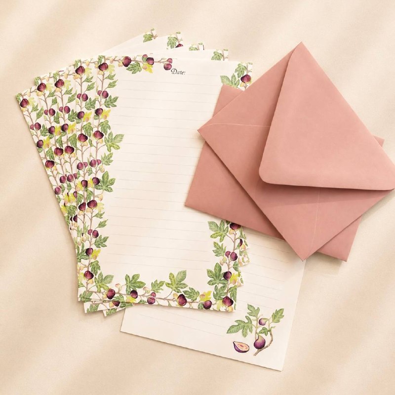 Fig-patterned writing sheets fanned beside two dusty-pink envelopes