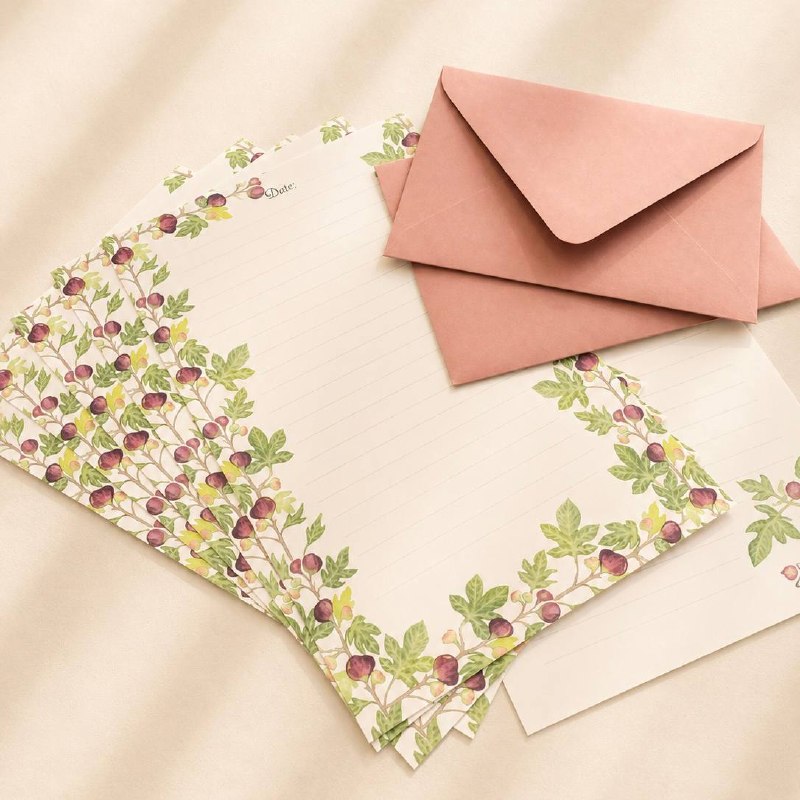 Fig-patterned writing sheets fanned out beside a dusty-pink envelope